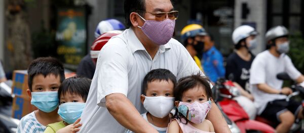 Người đàn ông có con đi xe đạp, đeo mặt nạ bảo vệ, trên đường phố Hà Nội, Việt Nam - Sputnik Việt Nam