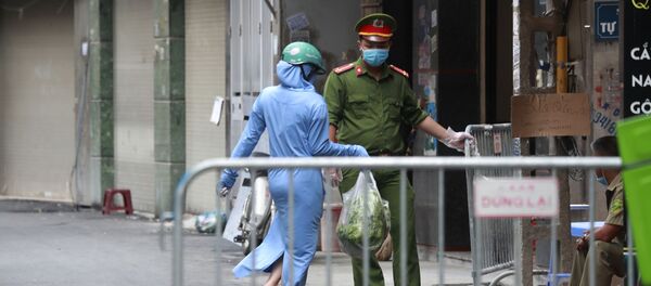 Một người phụ nữ mang thức ăn cho người thân của mình trong một khu dân cư bị đóng cửa do một trường hợp nhiễm coronavirus được xác nhận, Hà Nội - Sputnik Việt Nam