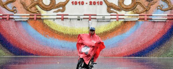 Người đàn ông đi xe máy trong trận mưa bão ở Hà Nội - Sputnik Việt Nam