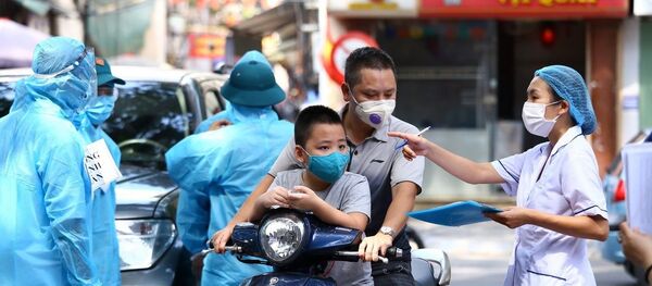 Nhân viên y tế hướng dẫn người dân xếp hàng theo phường đã đăng ký. - Sputnik Việt Nam