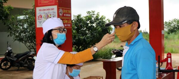 Nhân viên y tế kiểm tra thân nhiệt người tham gia giao thông tại Chốt kiểm tra Sao Mai. - Sputnik Việt Nam