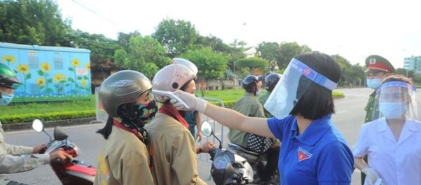 Đo nhiệt độ cho người dân tại chốt kiểm soát trên đường Trường Chinh lối vào thành phố Hải Dương. - Sputnik Việt Nam