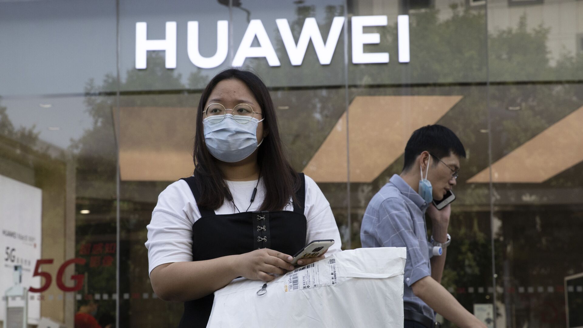 Cô gái đeo khẩu trang y tế trên nền của cửa hàng Huawei. Bắc Kinh - Sputnik Việt Nam, 1920, 16.04.2021