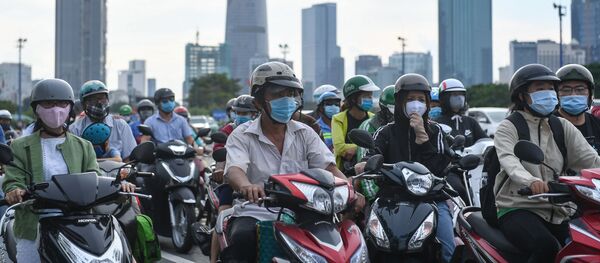 Người đeo khẩu trang đi xe máy  trước đèn hiệu giao thông ở Việt Nam. - Sputnik Việt Nam