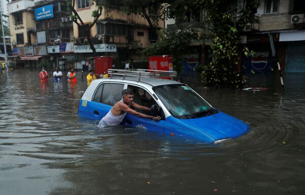 Một người đàn ông đẩy taxi trên con phố ngập lụt sau trận mưa bão ở Mumbai, Ấn Độ - Sputnik Việt Nam