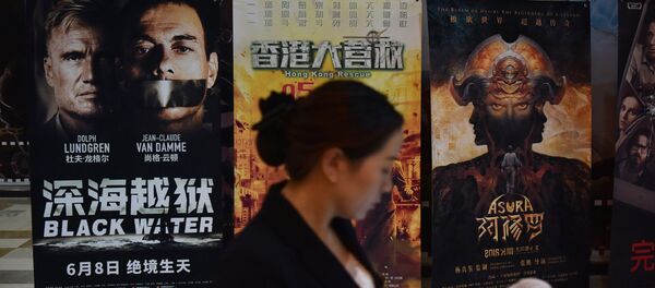 Một người phụ nữ nhìn vào điện thoại di động của mình gần áp phích phim bên ngoài rạp chiếu phim ở Bắc Kinh - Sputnik Việt Nam