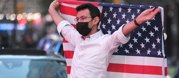 Người đàn ông với lá cờ Mỹ tại Quảng trường Thời đại ở New York sau tin ứng cử viên đảng Dân chủ Joseph Biden giành chiến thắng trong cuộc bầu cử tổng thống Mỹ - Sputnik Việt Nam