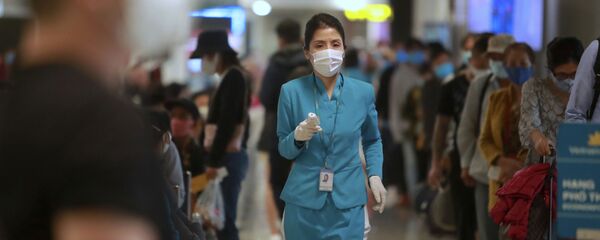Nhân viên hàng không cầm nhiệt kế tại sân bay Hà Nội, Việt Nam - Sputnik Việt Nam