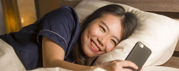 Cô gái Nhật Bản trẻ tuổi đang cười khi sử dụng điện thoại thông minh - Sputnik Việt Nam