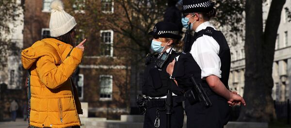 Cảnh sát đeo khẩu trang và những người phản đối lệnh hạn chế ở London, Anh. - Sputnik Việt Nam