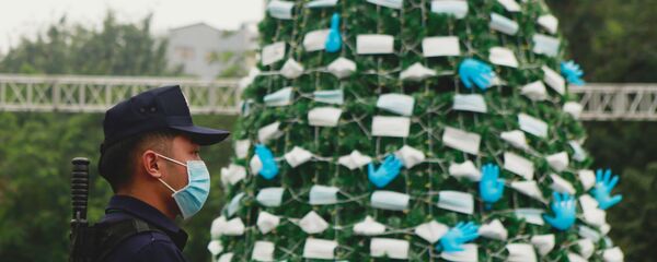 Nhân viên bảo vệ bên cây thông Noel được trang trí bằng khẩu trang và găng tay cao su ở Hà Nội, Việt Nam - Sputnik Việt Nam