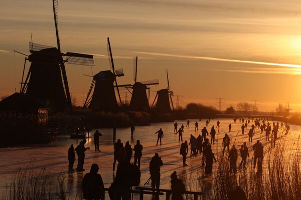 Mọi người trượt băng gần cối xay gió ở làng Kinderdijk, Hà Lan - Sputnik Việt Nam