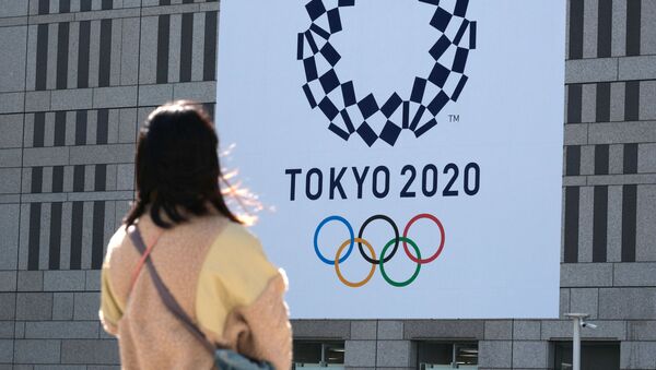 Cô gái nhìn vào biểu ngữ có logo của Thế vận hội Tokyo - Sputnik Việt Nam