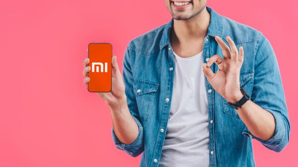 Chàng trai đang cầm trên tay một chiếc điện thoại thông minh Xiaomi. - Sputnik Việt Nam