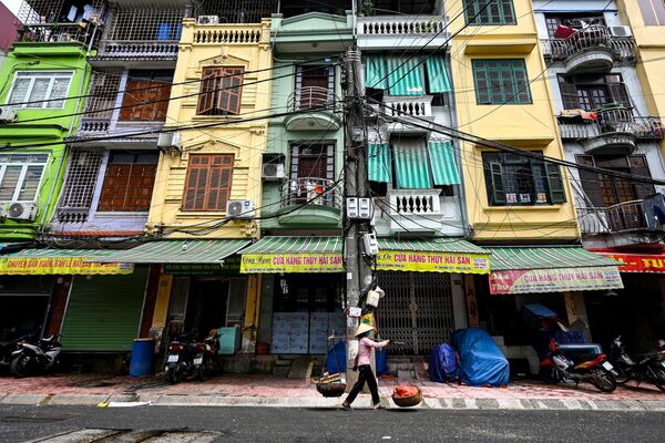 Một người bán hàng rong đi ngang qua khu chung cư chật hẹp nhà ống ở Hà Nội - Sputnik Việt Nam