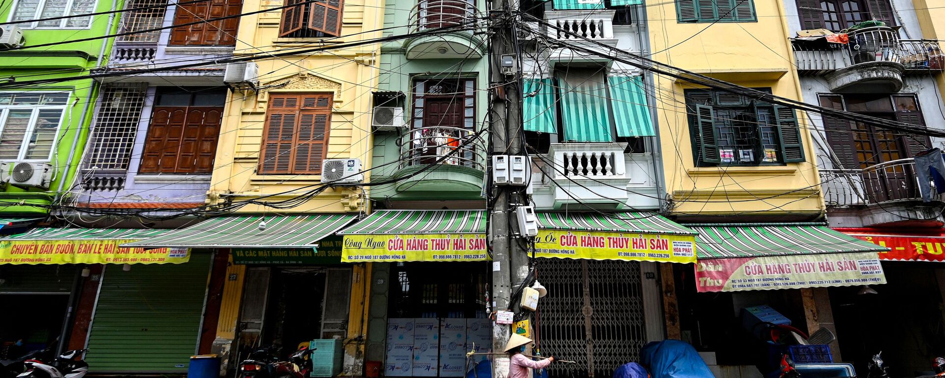 Một người bán hàng rong đi ngang qua khu chung cư chật hẹp nhà ống ở Hà Nội - Sputnik Việt Nam, 1920, 08.07.2022