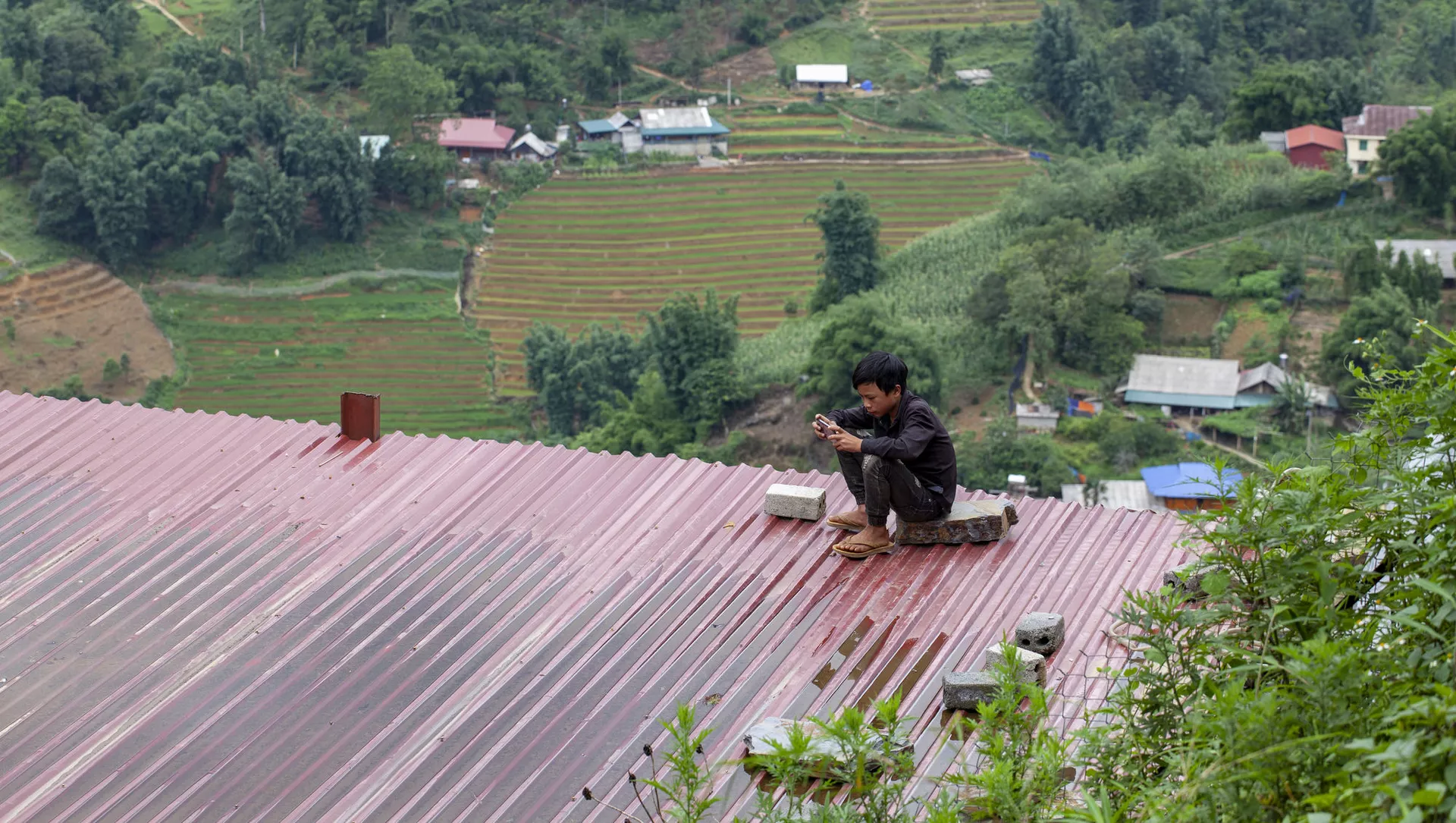 Cậu bé ngồi trên nóc tòa nhà với chiếc điện thoại thông minh, Việt Nam