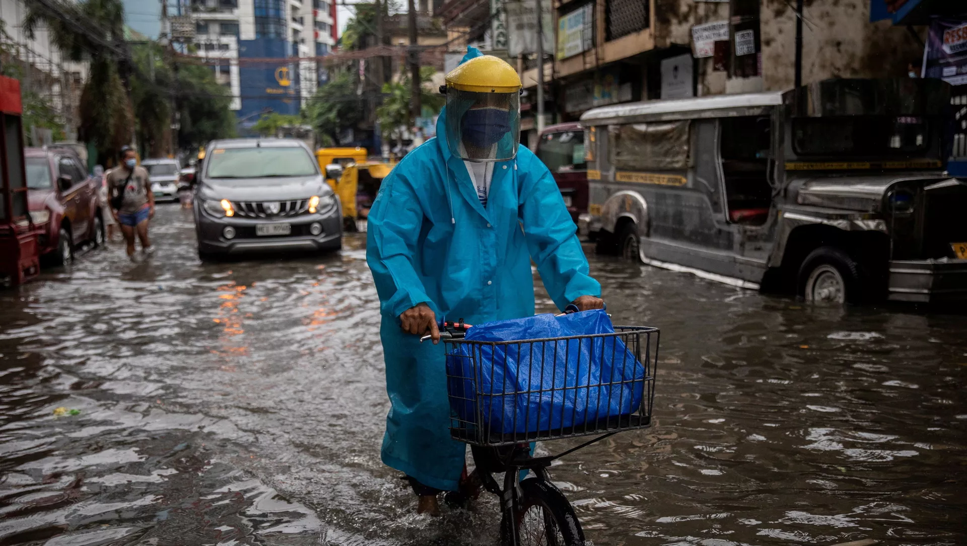 Một người đàn ông đeo mặt nạ đạp xe dọc con phố ngập lụt ở Manila, Philippines.