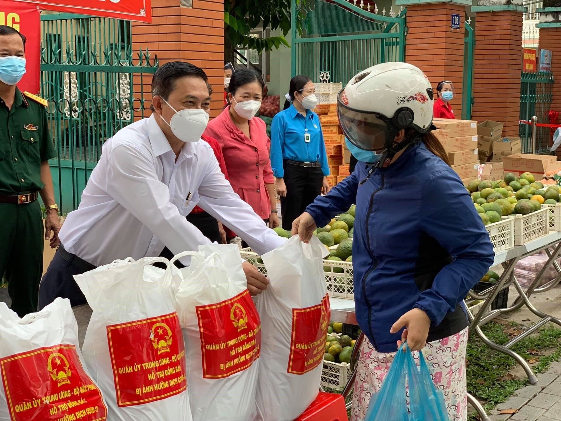 Chủ tịch Mặt trận Tổ quốc Việt Nam tỉnh Bình Dương Nguyễn Văn Lộc (mặc áo trắng) trao túi gạo cho người lao động tại Phiên chợ 0 đồng - Sputnik Việt Nam, 1920, 05.10.2021