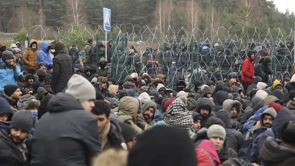 Người di cư trước hàng rào dây thép gai ở trạm kiểm soát Kuznitsa tại biên giới Belarus-Ba Lan - Sputnik Việt Nam