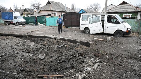 Hố đạn và chiếc ô tô bị hư hại do pháo kích ở quận Kievsky của Donetsk. - Sputnik Việt Nam