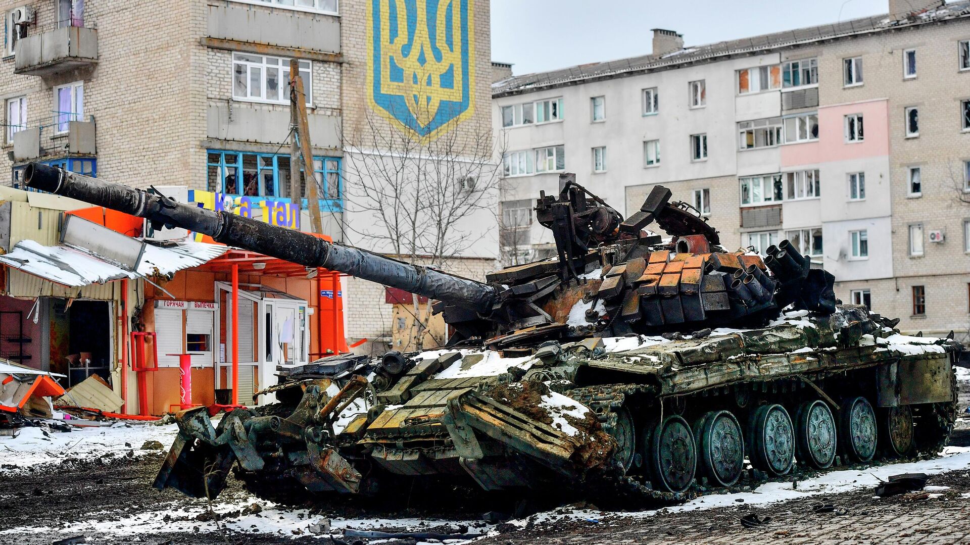 Xe tăng bị phá hủy của Lực lượng vũ trang Ukraine gần ngôi nhà có quốc huy Ukraine ở Volnovakha - Sputnik Việt Nam, 1920, 04.04.2022
