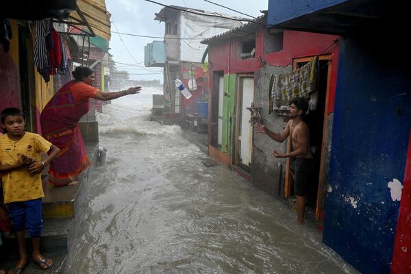 Một người dân ném chai nước uống cho người hàng xóm ở Mumbai. - Sputnik Việt Nam