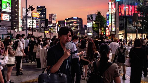 Một người đàn ông đi dạo với một chiếc quạt cầm tay ở Shinjuku, Tokyo - Sputnik Việt Nam