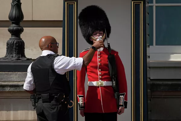 Người trực cho cảnh sát uống nước ở bên ngoài Cung điện Buckingham trong thời tiết nắng nóng ở London. Người trực cho cảnh sát uống nước ở bên ngoài Cung điện Buckingham trong thời tiết nắng nóng ở London. - Sputnik Việt Nam