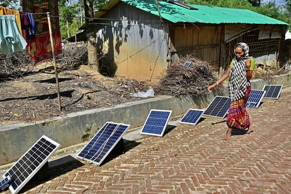 Người phụ nữ tị nạn Rohingya đi ngang qua các tấm pin mặt trời trên đường phố tại trại người Rohingya theo đạo Hindu ở Uhiya, Bangladesh. - Sputnik Việt Nam