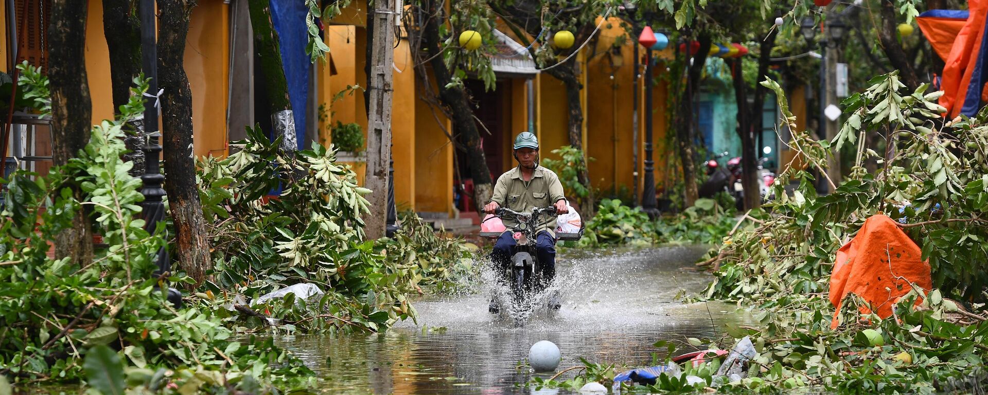 Người đàn ông đi xe trên đường phố ngập lụt sau khi cơn bão Noru đi qua tại thành phố Hội An, tỉnh Quảng Nam, Việt Nam - Sputnik Việt Nam, 1920, 15.10.2022