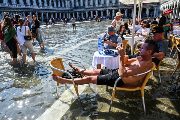 Khách du lịch ngồi trên sân thượng quán cà phê ở Piazza San Marco ngập lụt của Venice. - Sputnik Việt Nam