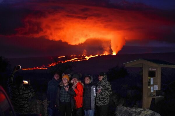 Mọi người tạo dáng trước dung nham phun trào từ núi lửa Mauna Loa ở Hawaii. - Sputnik Việt Nam