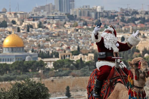 Một người Palestine hóa trang thành ông già Noel cưỡi lạc đà ở Jerusalem. - Sputnik Việt Nam