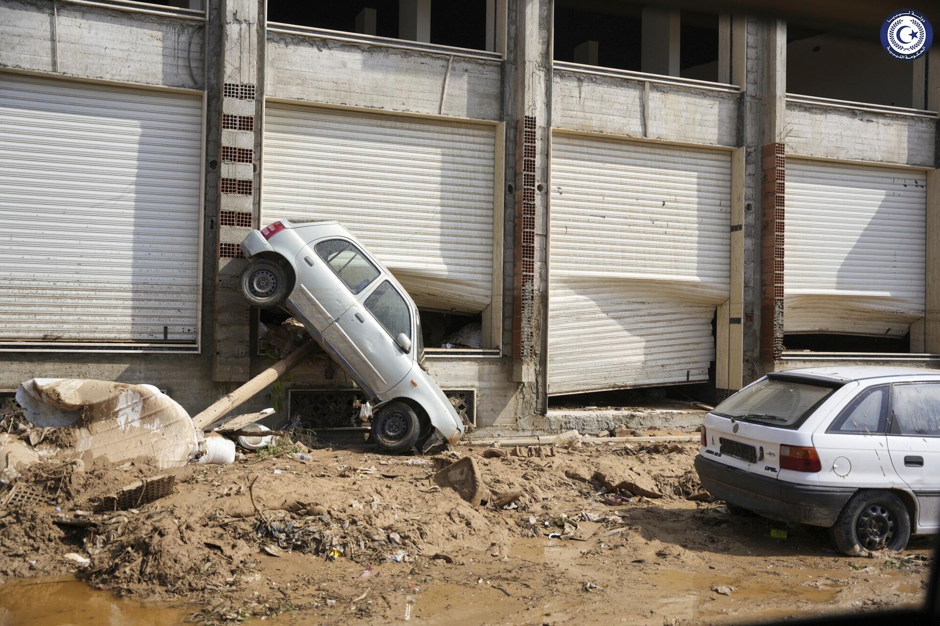 Một chiếc ô tô bị nước lũ cuốn vào phía trước một cửa hàng ở Derna, Libya - Sputnik Việt Nam, 1920, 13.09.2023