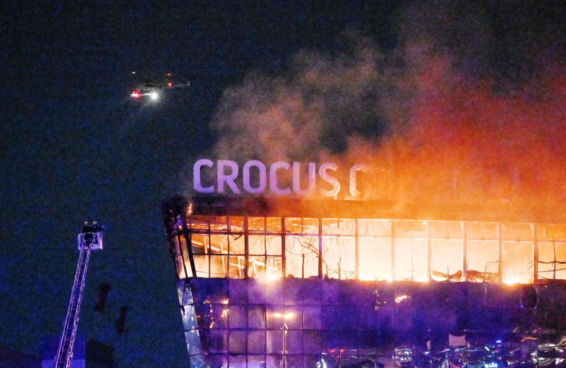 Lính cứu hỏa dập tắt mái nhà cháy của nhà hát Crocus City Hall, nơi vụ nổ súng xảy ra. - Sputnik Việt Nam, 1920, 12.03.2026