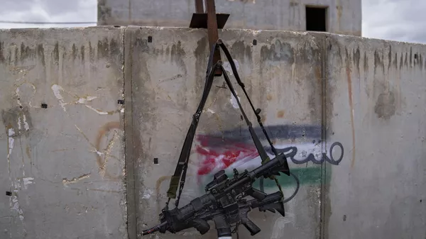 Hai khẩu súng trường M-16 treo trên tường với hình vẽ graffiti mô tả lá cờ Palestine tại Trung tâm Huấn luyện chiến tranh đô thị của IDF tại căn cứ quân sự Zeelim, miền nam Israel. - Sputnik Việt Nam