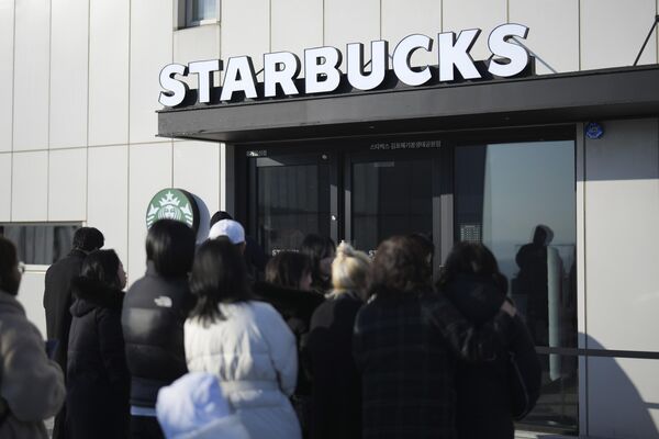 Du khách xếp hàng chờ vào quán Starbucks mới mở ở biên giới giữa Hàn Quốc và Bắc Triều Tiên nhìn vào CHDCND Triều Tiên - Sputnik Việt Nam