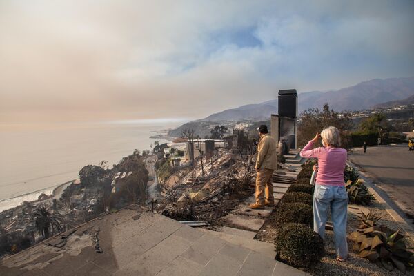 Mọi người nhìn những ngôi nhà bị thiêu rụi trong vụ cháy Palisades ở Los Angeles, California - Sputnik Việt Nam