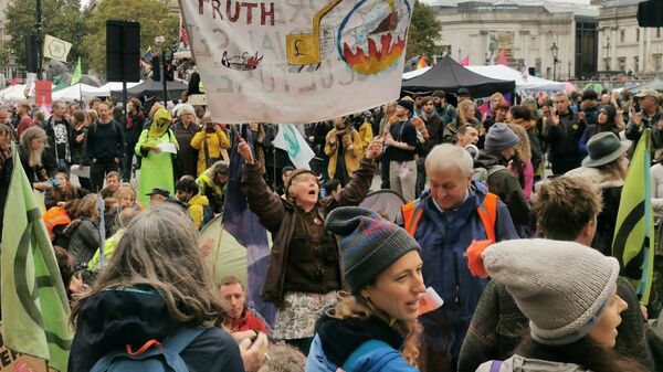 An activist holds a banner on climate change as protestors stage a sit in at a major road at Trafalgar Square in London, UK - Sputnik Việt Nam