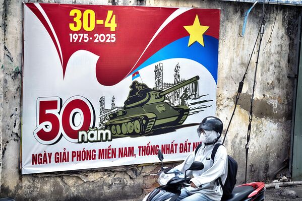 Người lái xe máy đi qua tấm biển quảng cáo kỷ niệm 50 năm ngày kết thúc Chiến tranh Việt Nam tại Thành phố Hồ Chí Minh, Việt Nam - Sputnik Việt Nam