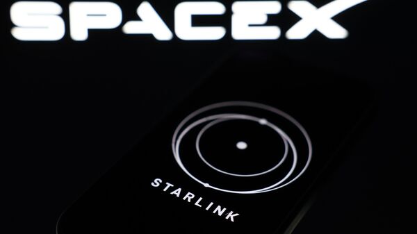 Смартфон со включенным приложением Starlink на фоне логотипа SpaceX - Sputnik Việt Nam