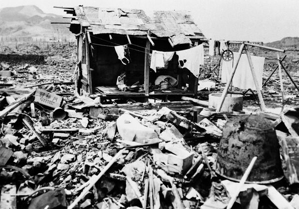 Một gia đình người Nhật đang ăn cơm trong căn lều tạm bợ dựng bằng các mảnh gạch vụn, tại nơi từng là ngôi nhà của họ ở Nagasaki. Ngày 14 tháng 9 năm 1945 - Sputnik Việt Nam