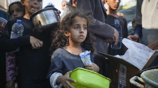 Một bé gái Palestine xếp hàng mua đồ ăn ở Deir al-Balah, Dải Gaza - Sputnik Việt Nam