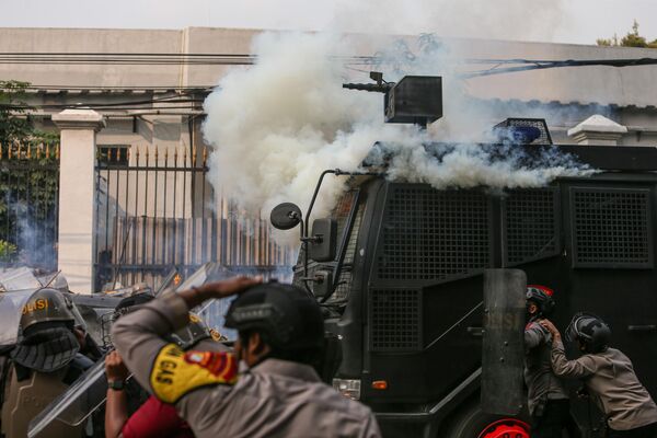 Cảnh sát ẩn nấp, tránh khí gas độc do người biểu tình ném ra trước trụ sở quốc hội Indonesia tại Jakarta, Indonesia - Sputnik Việt Nam