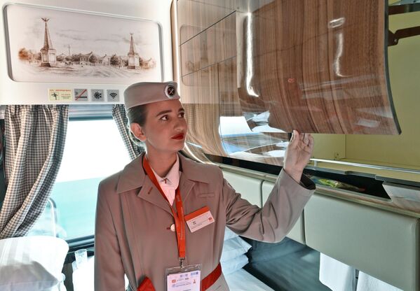 Nhân viên phục vụ của công ty Đường sắt Nga (RZD) giới thiệu các toa ngủ hạng sang mới (SV) tại triển lãm trong khuôn khổ hội chợ kỹ thuật và công nghệ đường sắt &quot;PRO//Dvizheniye.Ekspo&quot; diễn ra tại Saint Petersburg. Các toa xe được trang bị giường dài 2 mét, kệ để đồ xách tay lớn phía trên, buồng tắm, bàn là và bàn ủi. - Sputnik Việt Nam