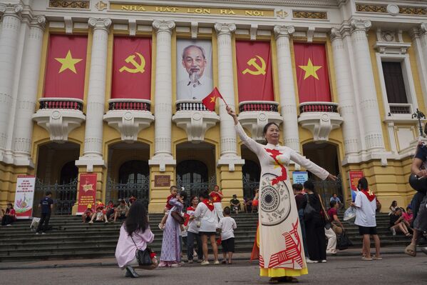 Người phụ nữ chụp ảnh trước Nhà hát Lớn, nơi các ban công được trang trí bằng cờ Việt Nam và cờ Đảng Cộng sản, tại khu phố cổ Hà Nội, Việt Nam - Sputnik Việt Nam