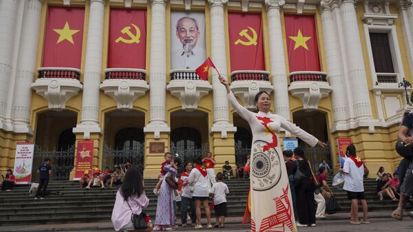 Người phụ nữ chụp ảnh trước Nhà hát Lớn, nơi các ban công được trang trí bằng cờ Việt Nam và cờ Đảng Cộng sản, tại khu phố cổ Hà Nội, Việt Nam   - Sputnik Việt Nam