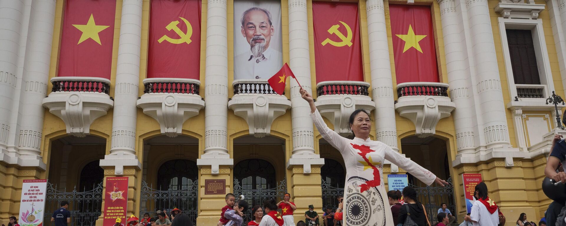 Người phụ nữ chụp ảnh trước Nhà hát Lớn, nơi các ban công được trang trí bằng cờ Việt Nam và cờ Đảng Cộng sản, tại khu phố cổ Hà Nội, Việt Nam   - Sputnik Việt Nam, 1920, 01.09.2025