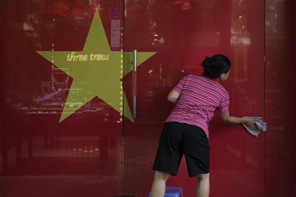 Người phụ nữ lau cửa kính có in hình lá cờ Việt Nam tại một cửa hàng trong khu phố cổ Hà Nội, Việt Nam - Sputnik Việt Nam